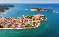 Luftaufnahme einer Küstenstadt mit historischen Gebäuden und blauem Meer.
