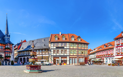 Mittelalterlicher Marktplatz mit Fachwerkhäusern und blauem Himmel.