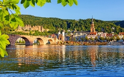 Historische Brücke und Skyline bei Tageslicht, Fluss im Vordergrund.