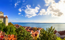 Mittelalterliche Burg und See unter blauem Himmel mit Wolken.