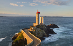 Leuchtturm auf Felsen im Meer bei Sonnenuntergang