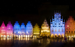 Bunte Fassaden von historischen Gebäuden bei Nacht mit Vollmond im Hintergrund.