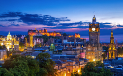 Skyline von Edinburgh bei Dämmerung mit Schloss und Uhrturm.