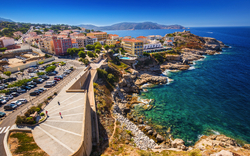 Küste und Hafenstadt in Calvi, Korsika, Frankreich mit bunten Gebäuden und klarem blauen Meer.