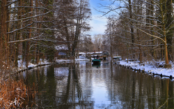 Verschneite Landschaft mit Fluss und Boot im Winter.