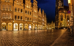 Beleuchtete Altstadt mit Kopfsteinpflaster und gotischer Kirche bei Nacht.