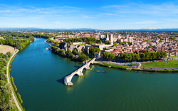 Luftaufnahme einer Flusslandschaft mit Stadt und Brücke bei klarem Himmel.