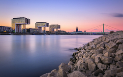 Stadtansicht von Köln mit Kranhäusern und Dom am Rheinufer bei Sonnenuntergang
