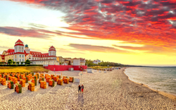 Strand mit Strandkörben und historischen Gebäuden bei Sonnenuntergang.